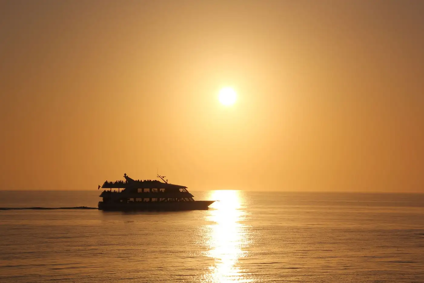 Sunset over the Gulf of Mexico seen from the bow of a small boat, amber sky reflected on glassy water